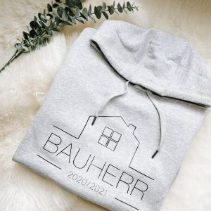 grau-melierter Hoodie mit Aufdruck "Bauherr" zusammengefaltet auf Schaffell