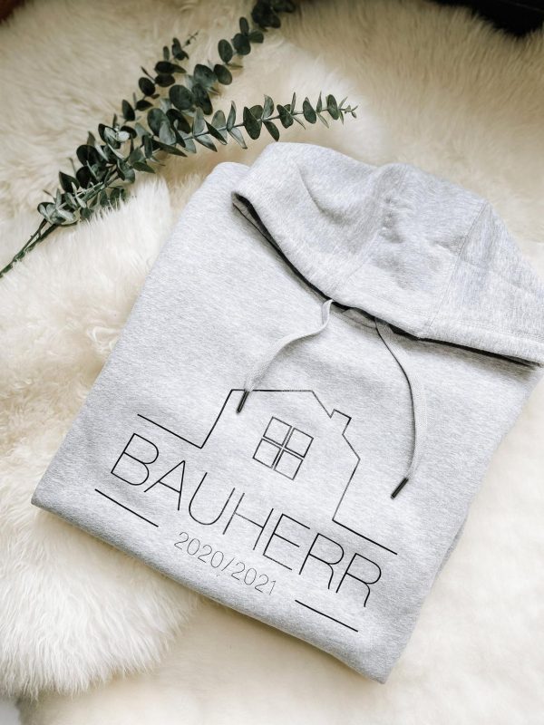 grau-melierter Hoodie mit Aufdruck "Bauherr" zusammengefaltet auf Schaffell